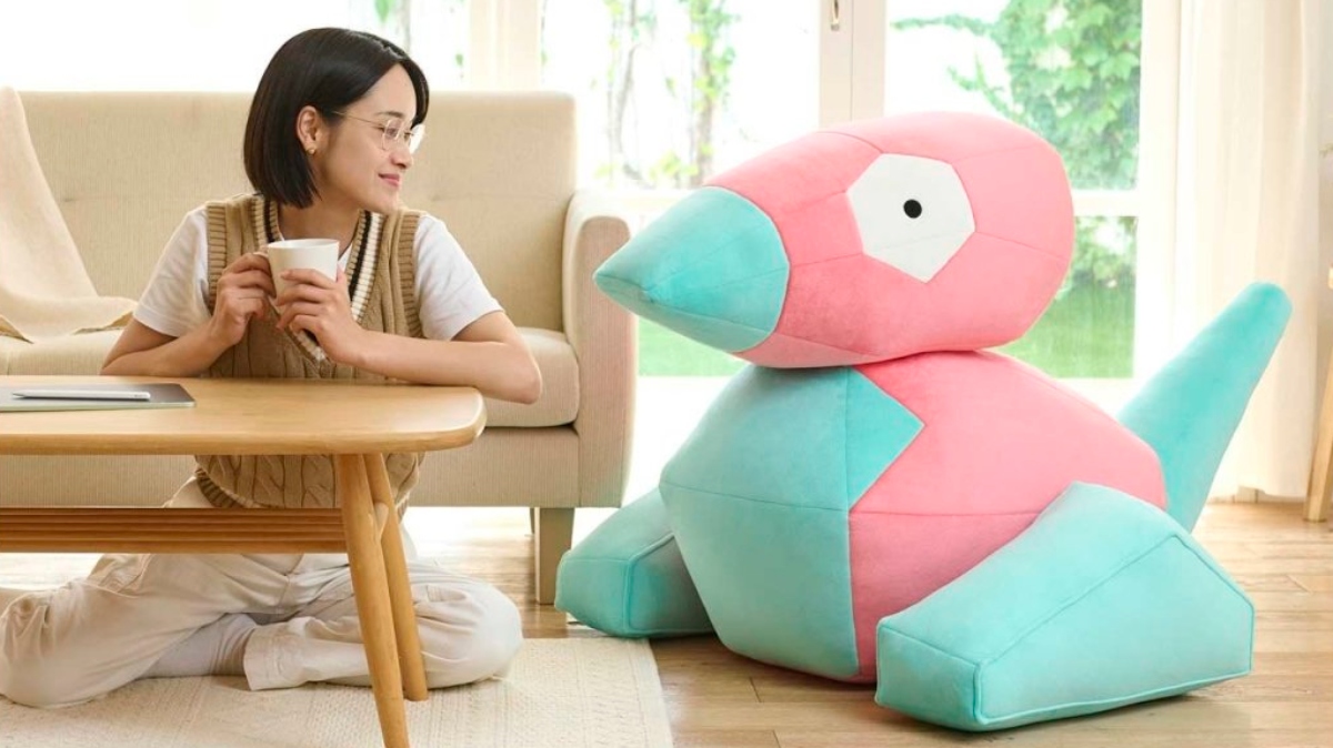 Image of a model sitting next to the Porygon life size Pokémon plush